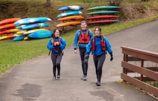 Ailsa McMillan and two other IDCORE students in wet suits, heading to the water